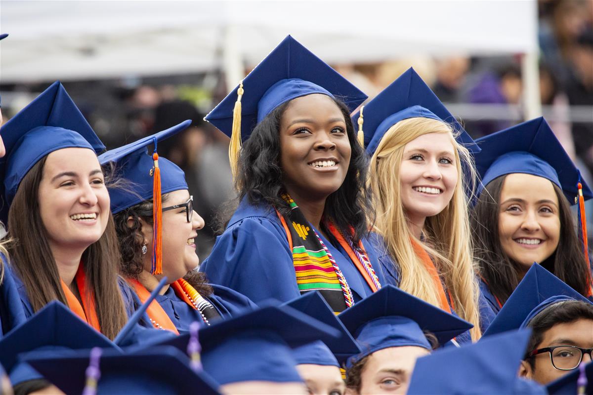 Female students watch the stadium video screen during the University of Illinois Commencement at Memorial Stadium, May 11, 2019.